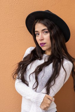 Uzun dalgalı saçlı, aksesuar olarak şapka takan genç bir kadın model, Latin kadın moda ve güzellik, göz alıcı insan portresi