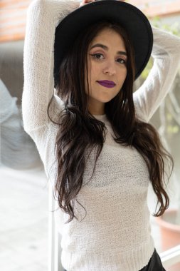 Uzun dalgalı saçlı güzel Latin bir kız, modaya uygun siyah bir şapka takıyor, yaşam tarzı ve moda, doğal güzellik