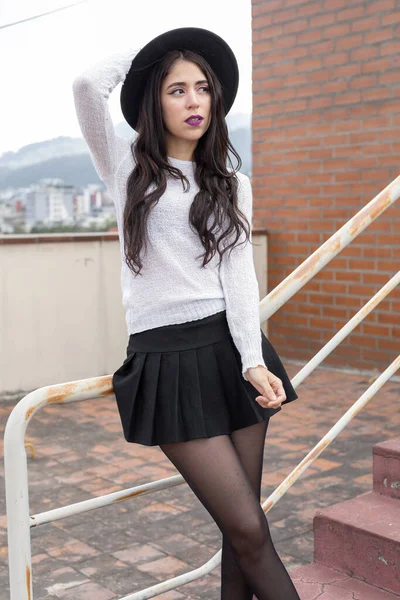 Terasta rahat duran bir kişi, günlük kıyafetler giyen genç Latin bir kadının yaşam tarzı, bacak bacak üstüne atmış bir model.