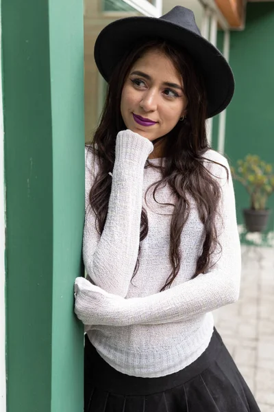 cheerful latin woman with black hair with hair, wearing a makeup and hat, beauty and lifestyle of young model, model with details on her face