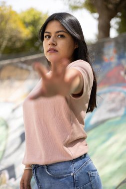 Dur işaretini elleriyle yapıyor. Gündüz siyah saçlı genç bir Latin kadın. Şehir yaşam tarzı, palmiyeyi gösteren ifade biçimi.