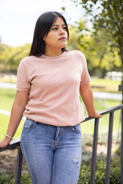 Uzun saçlı, rahat bir hayat tarzı olan arka plandaki ağaçlarda, gençlik güzelliğinde ve modasında, çekici Latin bir kadın.