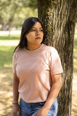 Ağaç kabuğuna yaslanmış güzel bir Latin kadınla yaz günü. Doku, güzellik ve doğa. Yüzün ayrıntıları.