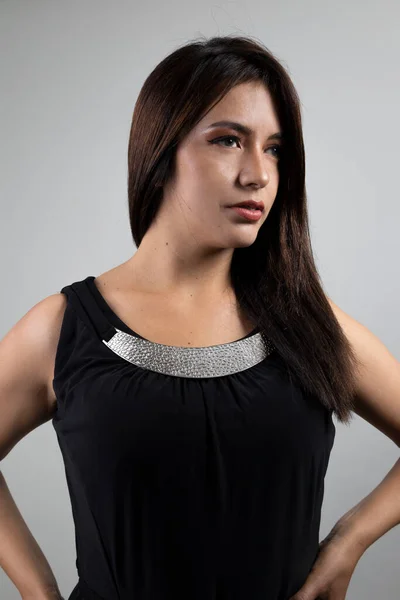 details of glamorous latin woman wearing black dress with metallic details in studio, fashion and beauty in young person portrait, lifestyle