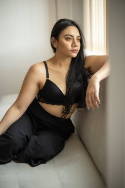 Rahat bir şekilde kanepede oturuyor, uzun düz saçlı Latin kadın, doğal güzellik ve gençlik modası, çekici model, yaşam tarzı