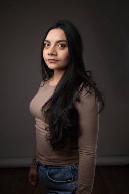 Stüdyoda poz veren genç bir bayan model, uzun siyah saçlı Latin bir kadın.