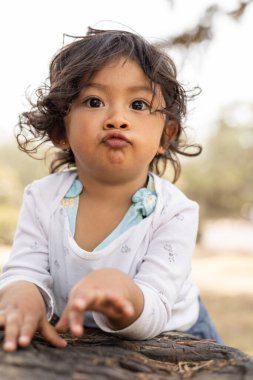 Yüz ayrıntıları kıvırcık saçlı küçük Latin kız öpücük hareketi yapıyor, çocukluk ve sevgi göstergesi, sevimli yüz ifadeleri