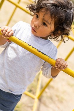 Küçük kıvırcık saçlı kız parkta oyun oynuyor. Yüzünün, çocukluğunun ve yaşam tarzının ayrıntıları.