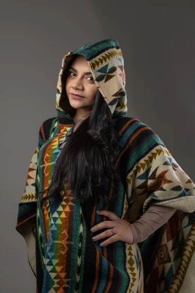 natural beauty and fashion with latin american culture poncho with hood, colorful and warm clothes wearing by young latin woman with black eyes and hair