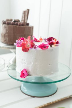 Krema ve yenilebilir gül yapraklarıyla süslenmiş kekler ve çikolata, stüdyodaki kutlamalar için tatlı yiyecekler, pasta ve tatlı