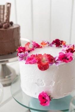 Lezzetli pastalar, krema ve yenilebilir gül yapraklarıyla süslenmiş, diğeri çikolatalı, stüdyoda kutlama için tatlı yiyecekler, pastane