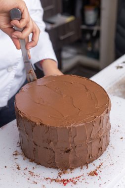 Pasta işinde çalışmak, çikolatalı pastayı kakao kremiyle süslemek, lezzetli bir tatlı.