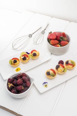 Stüdyoda güzel bir pasta süslemesi servis masasında karıştırmak için mutfak gereçleri tatlı aperatiflerle mutfak duvar kağıdı, malzeme olarak çilek.
