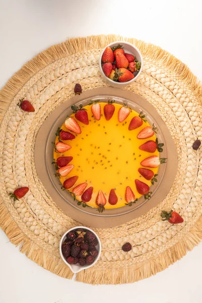 passion fruit cheesecake decorated with strawberries and fresh blackberries on a table ready to eat, sweet dessert in studio, plate decoration