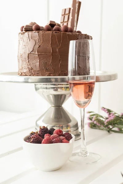 studio photo with food and drink decorated for elegant celebration, beautiful chocolate cake, fruits and a full glass