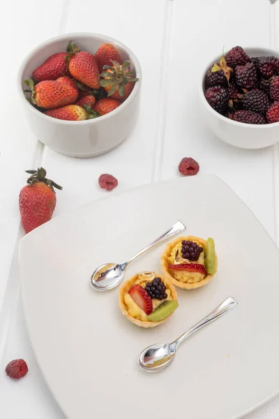 details of dessert decorated with strawberries, blackberries and pastry cream, wallpaper of elegant plates with silver spoons, pastries