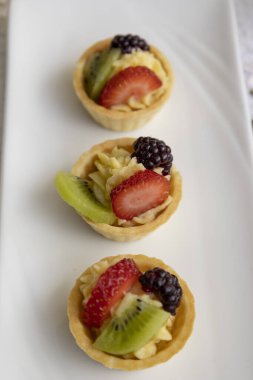 Stüdyoda detaylı dokusu olan duvar kağıdı, tropik meyve ve kremayla süslenmiş bir tabakta servis edilen gurme yemeği, pasta.