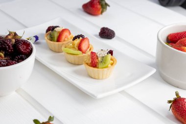 Tatlı kremalı meyveli turta, atıştırmalık olarak iştah açıcı tatlı yemek, tabakların zarif dekorasyonu, masa kağıdı.