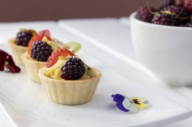 Tabakların zarif dekorasyonu, tropik meyveler, tatlılar ve tatlı tatlı tarzıyla süslenmiş duvar kağıdı, yemek servisi.