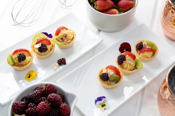 sweet dessert, catering service in studio, appetizing and delicious cupcakes with pastry cream and strawberries and blackberries in bowls, wallpaper