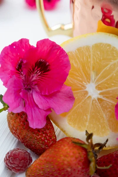 texture of lemon slice and fresh strawberries, citrus fruits in studio with a natural flower, beauty and style