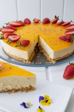 Masada bir parça cheesecake ve kek, tutku meyveli gurme tarzı pasta süslemesi, stüdyoda nefis taze yemek.