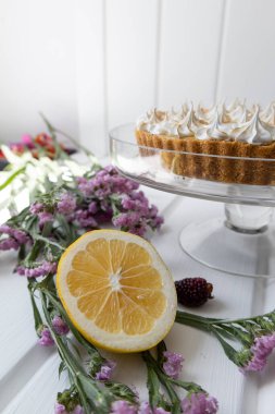 Süs olarak pasta kremalı çikolatalı pasta masada doğal bir çiçek ve bir dilim taze limon var.