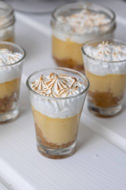 Bardağın kremalı ve tarçınlı dekorasyonu, beyaz arka planda iştah açıcı tatlıların dekorasyonu, tatlılar ve pasta, yiyecek ve içecekle yapılan şekerlemeler.