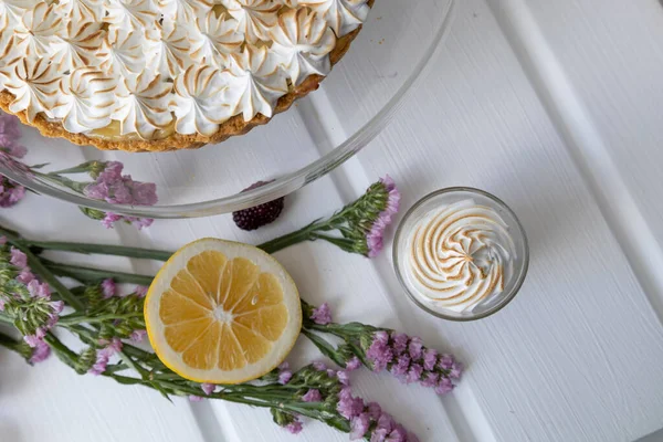 delicious cake with flamed pastry cream as decoration, on the table is a natural flower and a slice of fresh lemon, cooking ingredients