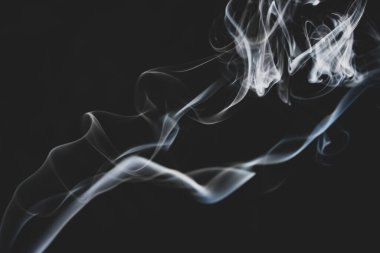 Siyah arka planda havada süzülen soyut duman