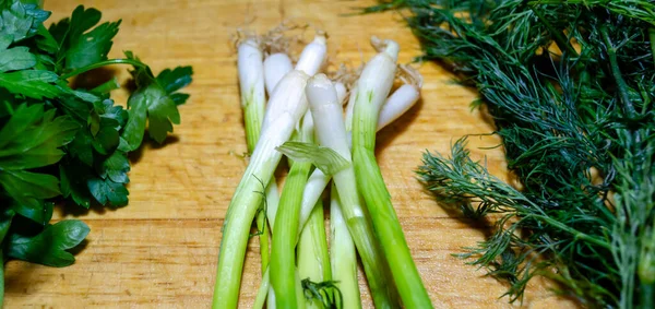 Sheaves of green onions, parsley and dill on a wooden cutting board — Stock Photo, Image