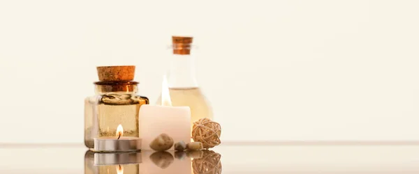 Concise spa composition with oil flasks and candles on beige background. — Stock Photo, Image