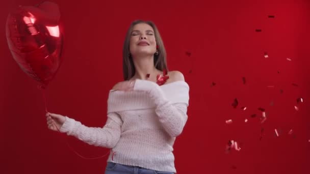 Young cute happy woman with red balloon enjoys falling confetti — Stock Video