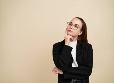 Bej arka planda genç bir kadın bir şey düşünüyor.