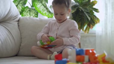Sevimli küçük kız evde plastik bloklarla oynuyor..