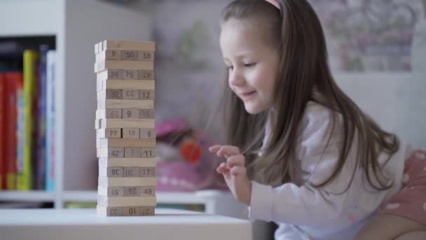 Curious little girl accidentally crashes tower of wooden blocks — Stock Video