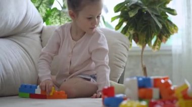 Sevimli küçük kız evde plastik bloklarla oynuyor..