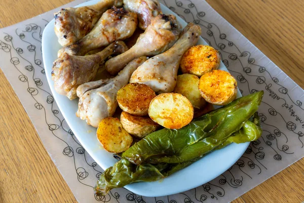 Büyük bir tabak kızarmış tavuk budu, patates kızartması ve yeşil biber..