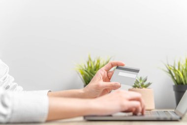 Dizüstü bilgisayar kullanan ve kredi kartını elinde tutan bir kadın.