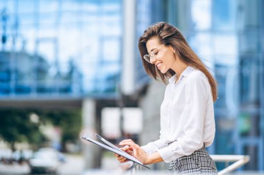 Modern iş merkezinin yakınında tablet kullanan bir iş kadını