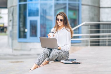 İş merkezinin yakınındaki laptopta çalışan genç bir iş kadını.