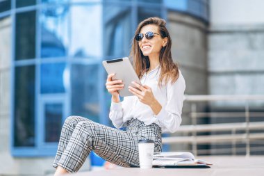 İş merkezinin yakınındaki tablette çalışan genç bir iş kadını.