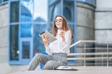 İş merkezinin yakınındaki tablette çalışan genç bir iş kadını.