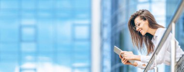 Modern iş merkezinin yakınında tablet kullanan bir iş kadını