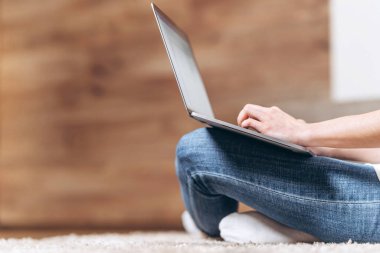 Kız evde oturuyor ve internette bilgisayarını karıştırıyor. 