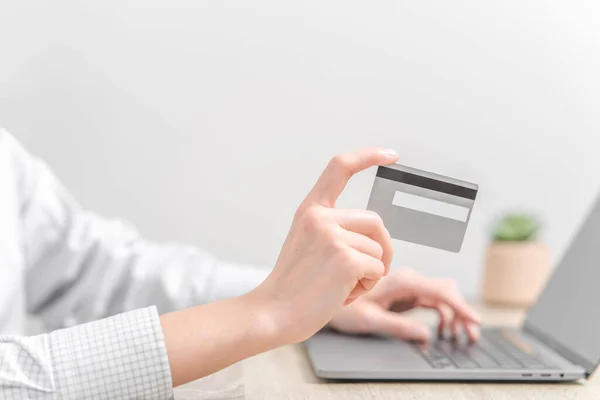 Woman using laptop and holding credit card in hands