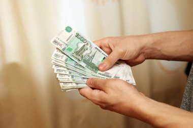 Bir tomar para, 100 ruble değerinde banknotlar genç bir adamın elinde. Moskova. 01.03.2019