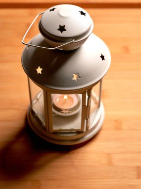 Tahta bir yüzey üzerinde mum olan beyaz bir fener..