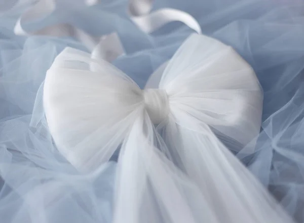 Large white bow with satin ribbon on pastel blue backgroung. Wedding bow belt. Baby shower background