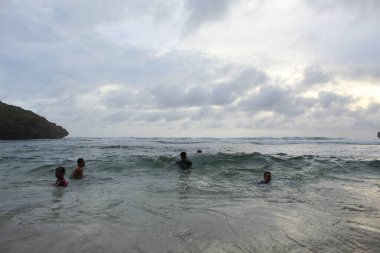 Asyalı çocuklar dalgaların arasında eğleniyor.